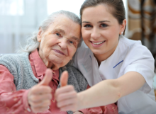 caregiver with elder patient giving thumbs up